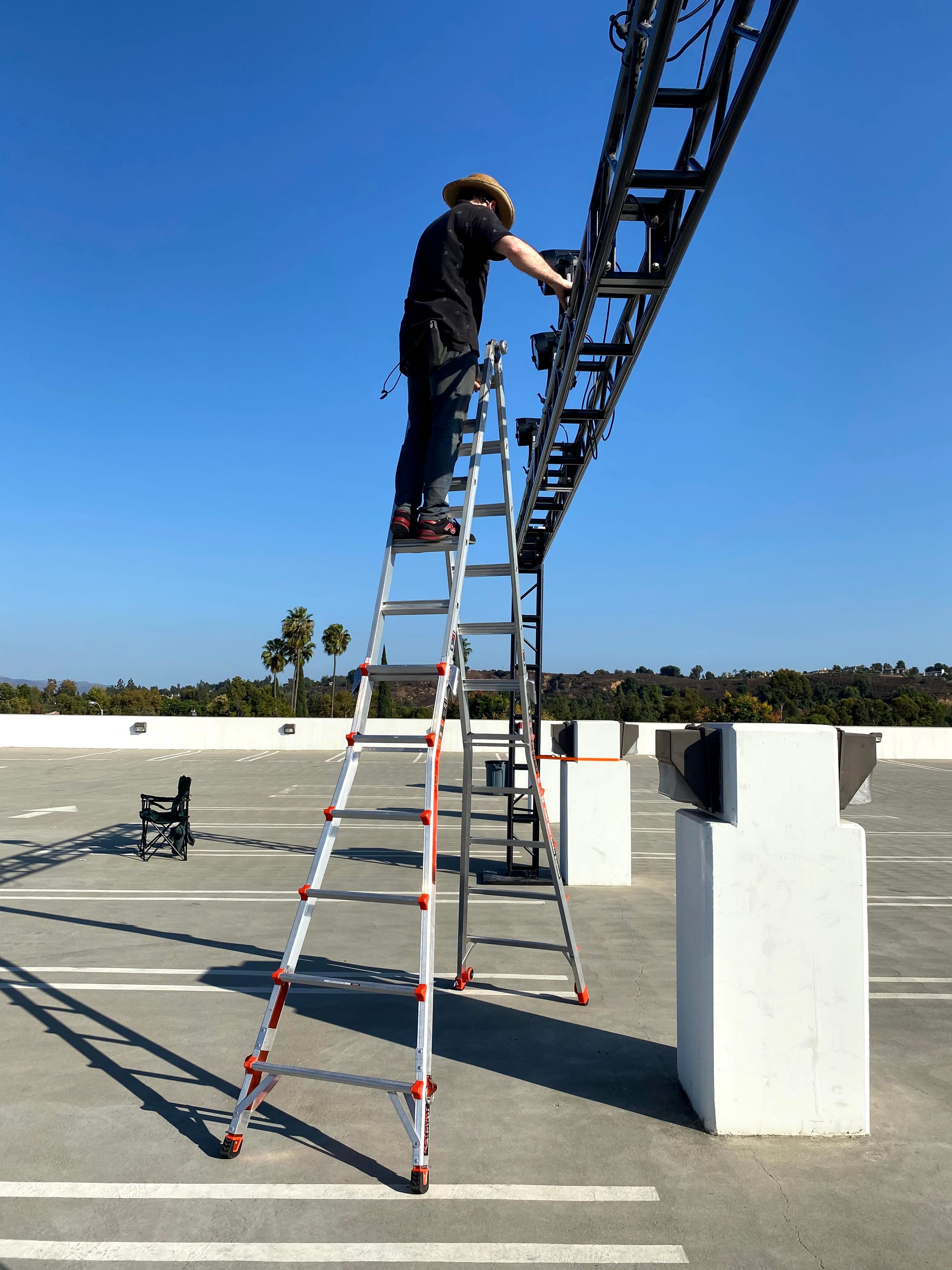 Person on a ladder installing lighting on a truss
