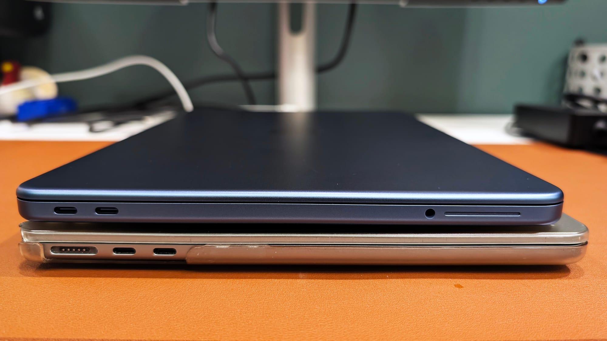 Side view of MacBook Neo on top of MacBook Air M2 highlighting USB-C ports and design differences
